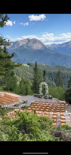 an outdoor ceremony set up on top of a hill with mountains in the background and trees around it