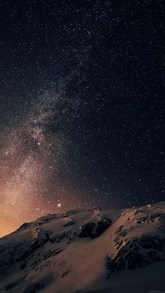 the night sky is filled with stars above snow covered mountains and rocks in the foreground