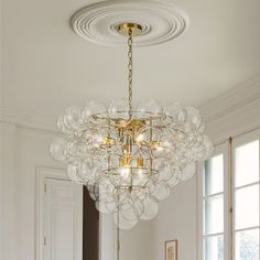 a chandelier hanging from the ceiling in a room with white walls and windows