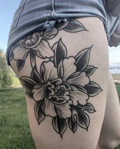 a woman's thigh with black and white flowers on the back of her leg