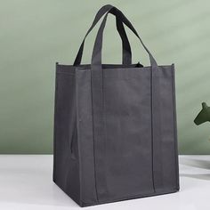 a gray bag sitting on top of a table next to a vase with flowers in it