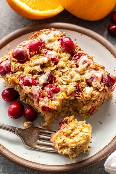 two pieces of granola on a plate next to an orange and some cranberries