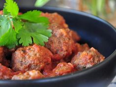 meatballs with tomato sauce and parsley in a bowl