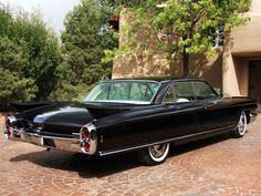 an old black car parked in front of a house