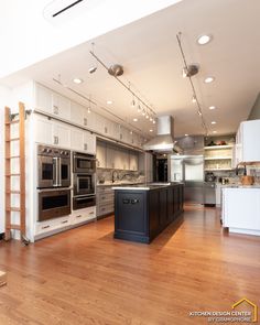 an empty kitchen with white cabinets and stainless steel appliances in the center, surrounded by wood flooring