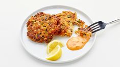 two crab cakes on a plate with lemon wedges