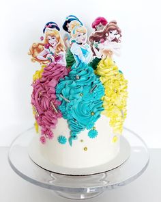 there is a cake decorated with princesses on the top and bottom tiers that are multicolored