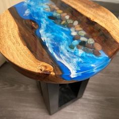 a wooden table with blue and black paint on the top that has rocks embedded in it