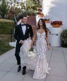 a bride and groom walking down the sidewalk