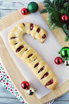 a pastry shaped like a wormel sitting on top of a cutting board next to christmas decorations