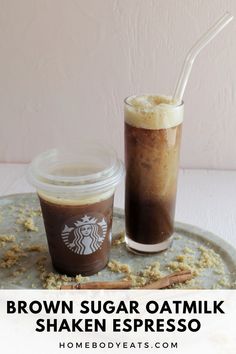 a cup of coffee next to a drink on a tray with cinnamon sticks and sugar