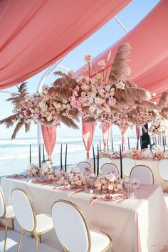 the tables are decorated with pink flowers and feathers