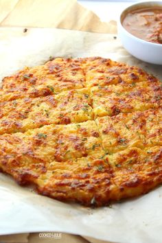 a pizza sitting on top of a piece of paper next to a bowl of sauce