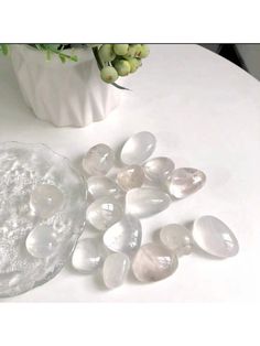 some clear rocks are sitting on a table next to a vase with flowers in it