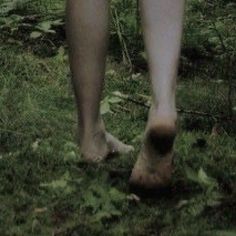 a person walking in the grass with their bare feet