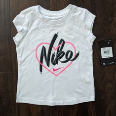 Nike Toddler Girl Tee Shirt 100% Cotton, Nike Print On Front With Pink Heart. Bundle To Save More! Cute Nike White Tops, Cute White Top With Logo Print, Cute White Tops With Logo Print, Cute Nike Short Sleeve Tops, Cute White Nike Top, Nike Toddler Girl Outfits, Nike Sports T-shirt With Screen Print, Cheap Nike Graphic Tee T-shirt, Shirt Kids Nike