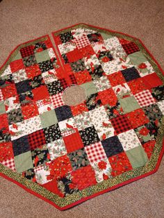 a red and black quilted table top on the floor next to a brown carpet