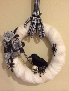 a halloween wreath hanging on the wall with skeleton hands and flowers attached to it's front