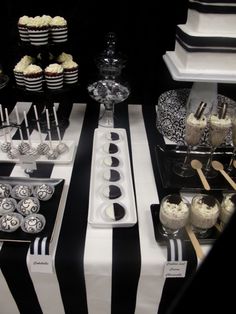 an assortment of desserts and cupcakes displayed on a black and white striped tablecloth