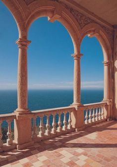 an outdoor area with pillars and tiled flooring overlooking the ocean on a sunny day