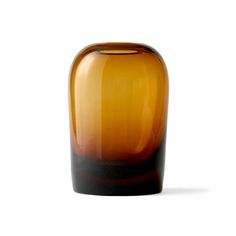 a brown glass vase sitting on top of a white table next to a black object