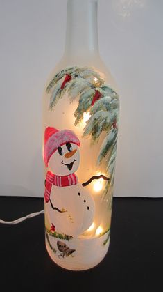 a lighted glass bottle with a snowman on it