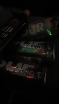 several cans of soda are stacked on top of each other in the dark, with one lit up