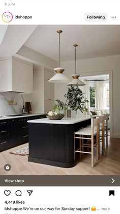 a kitchen with an island and two pendant lights hanging from it's ceiling above the counter