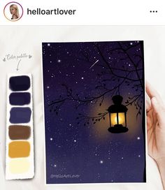 a person holding up a card with a lantern on it next to some paint swatches