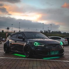 a black car with green lights on it's hood parked in a parking lot