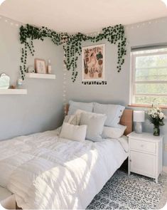 a white bed sitting in a bedroom next to a window with ivy growing on it