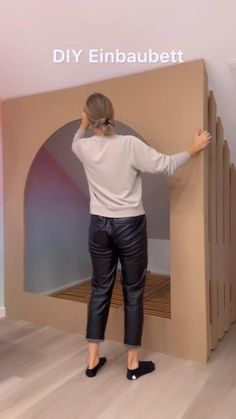 a woman standing in front of a cardboard arch with her hands on the back wall