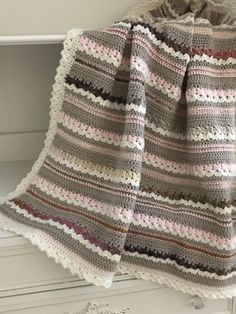 a crocheted blanket sitting on top of a white cabinet