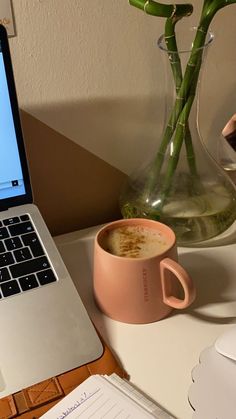 an open laptop computer sitting on top of a desk next to a cup of coffee