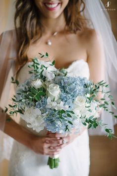 a bride holding a bouquet of blue and white flowers