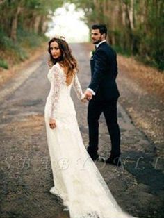 a bride and groom holding hands while walking down the road in their wedding dress with long sleeves