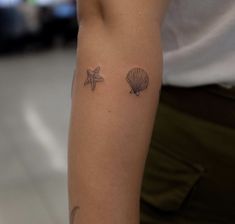 a woman's arm with two seashells and starfish tattoos on it