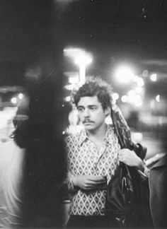 black and white photograph of two men standing next to each other on the street at night