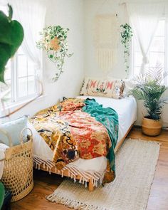 a bedroom with white walls and wooden floors has plants on the wall above the bed