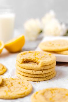 a stack of lemon cookies next to a glass of milk and some sliced lemons