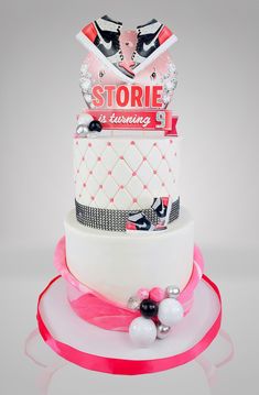 a three tiered cake with pink ribbon and decorations on it's top layer