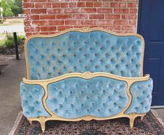 a blue couch sitting on top of a rug next to a brick wall and door