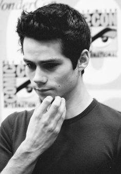 black and white photograph of a young man holding his hand to his face while looking at the camera