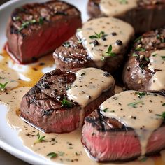 steaks with sauce and herbs on a white plate