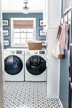 a washer and dryer in a laundry room with blue walls, black and white tile floor