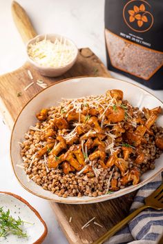 a white bowl filled with rice and meat next to a bottle of wine on a wooden cutting board