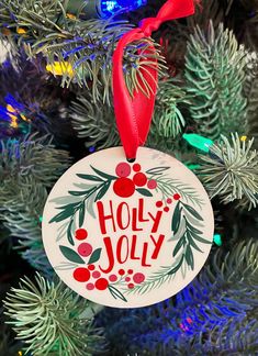 a christmas ornament that says holly jolly hanging from the top of a tree