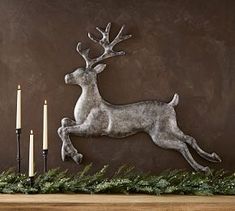 a metal deer with antlers and candles on a mantle