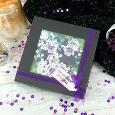 a purple and black box with flowers on it sitting next to some confetti