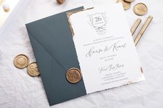 the wedding stationery is laid out on top of some waxed paper and gold coins